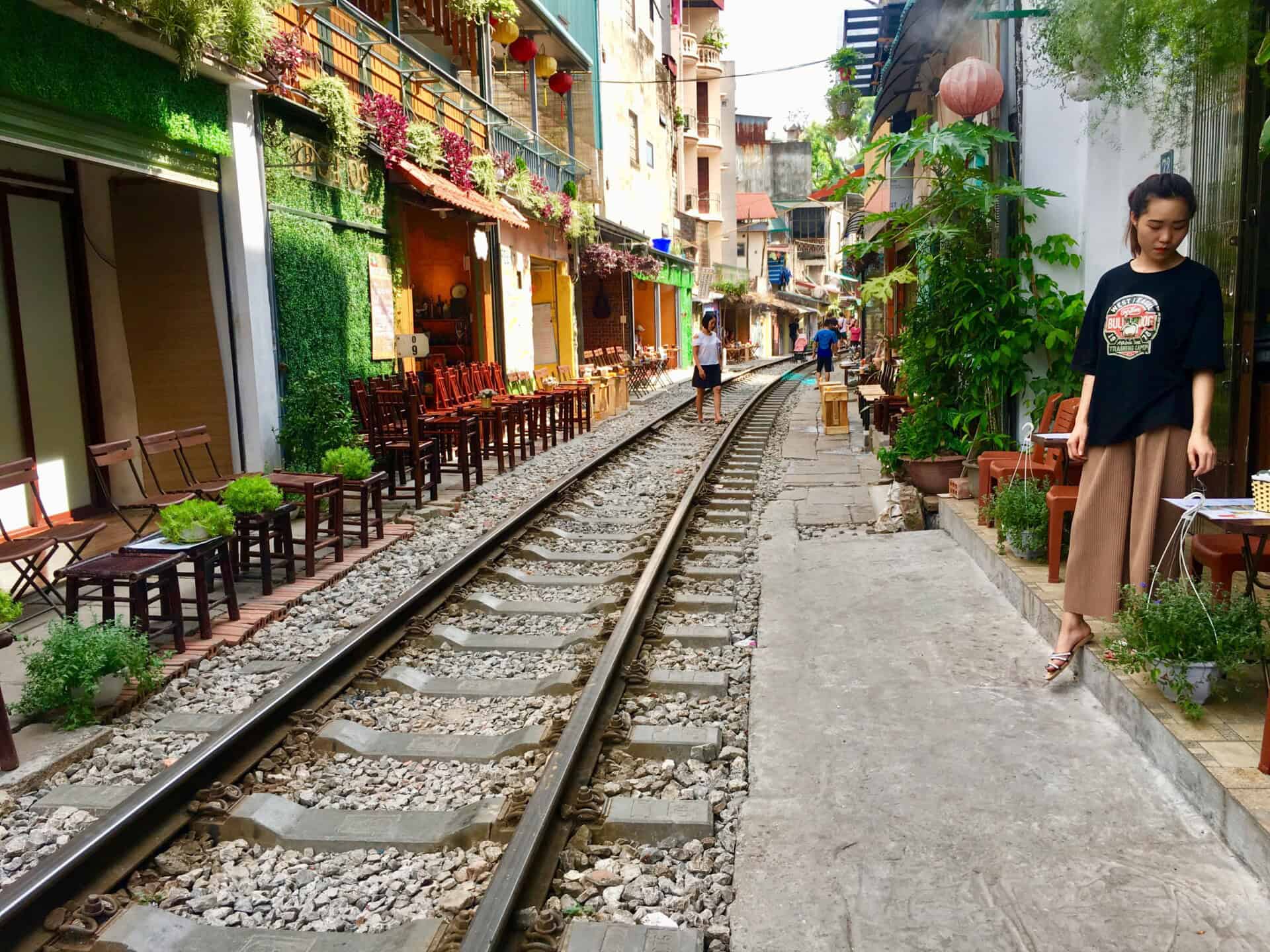 Togskinner gennem smal by, caféer på begge sider.