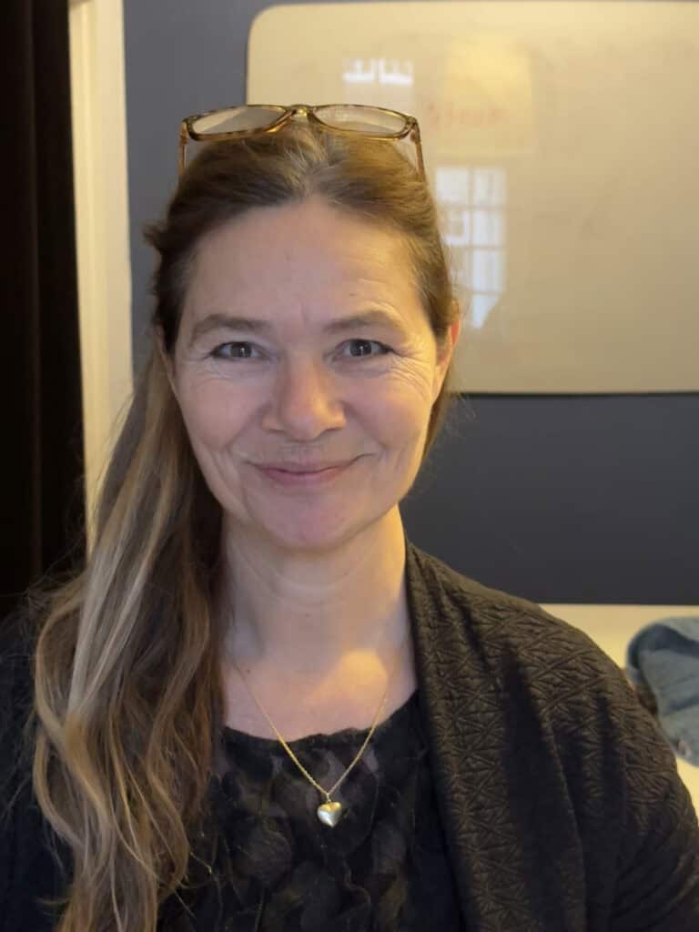 Kvinde med briller smiler foran whiteboard