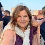 Kvinde smiler ved en udendørs begivenhed.