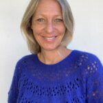 Kvinde med blåt strik og smilende ansigt.