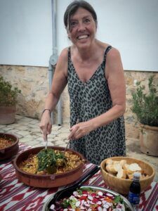 Kvinde serverer lækker mad ved festlig borddækning.