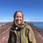 Kvinde med smil på klippebakke ved havet.