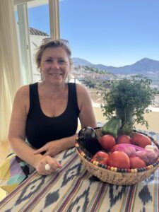 Kvinde sidder ved bord med grøntsager i skål.